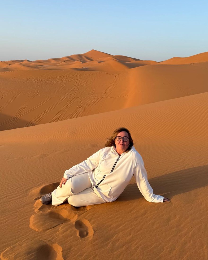 Mayte Sisó, fundadora de Nomaden, sentada en una duna del erg marroquí al atardecer