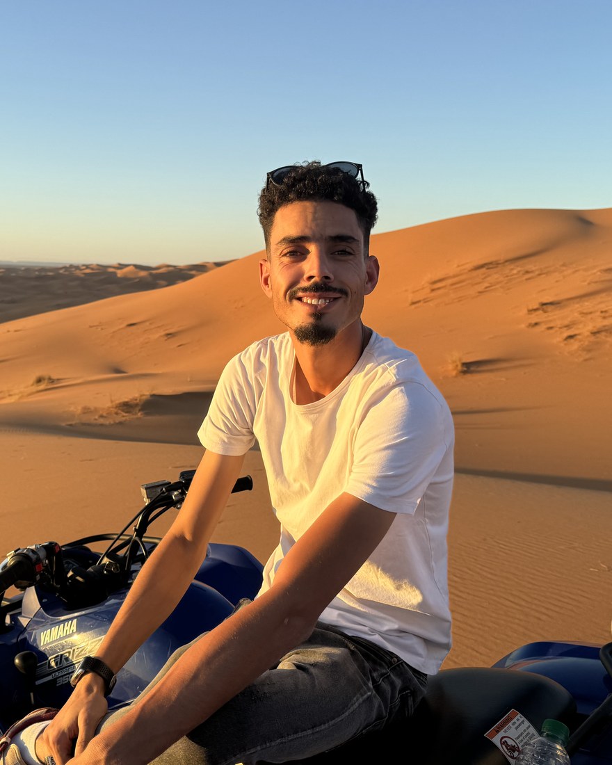 Zaid Aghdaoui, responsable en destino en Marruecos, sobre un quad en las dunas del Erg Chebbi al atardecer